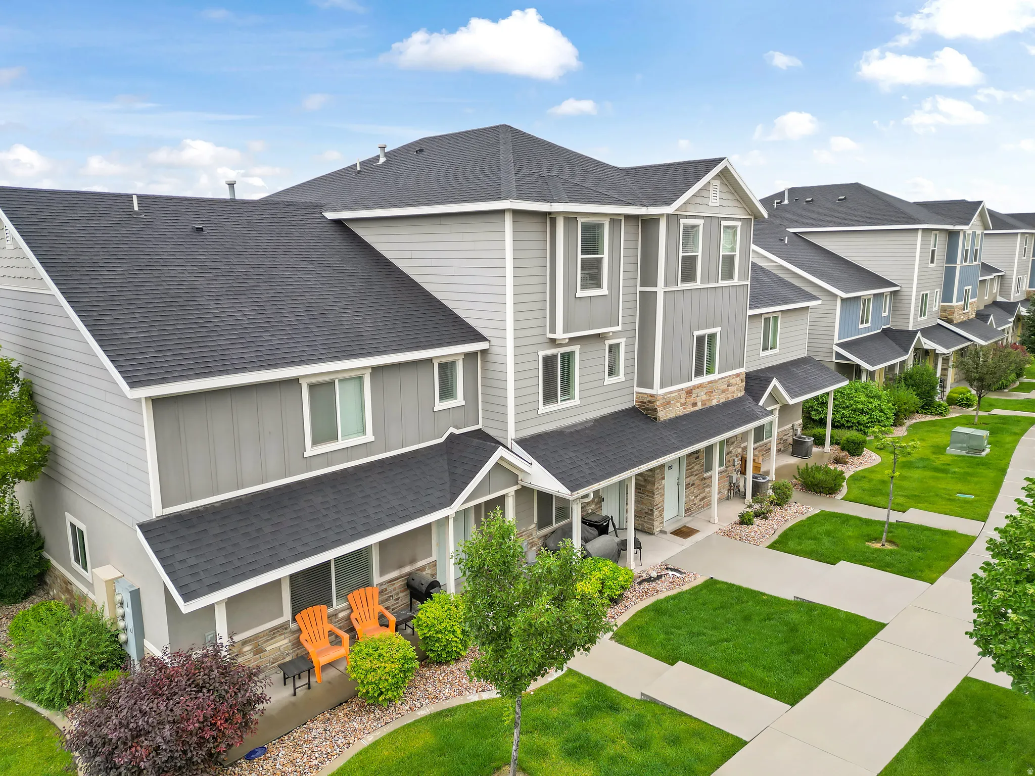 Contemporary townhome architecture featuring gray siding, stone accents, and dark shingle roofing