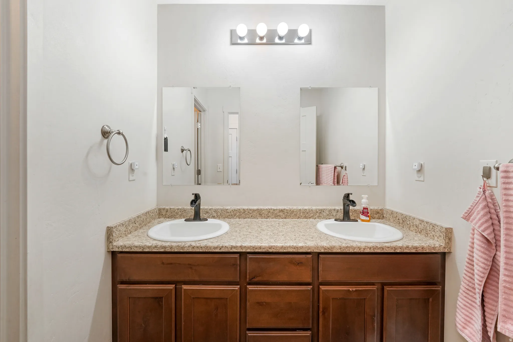 Dual vanity featuring a laminate countertop, two undermount sinks, and dark wood-finish cabinetry
