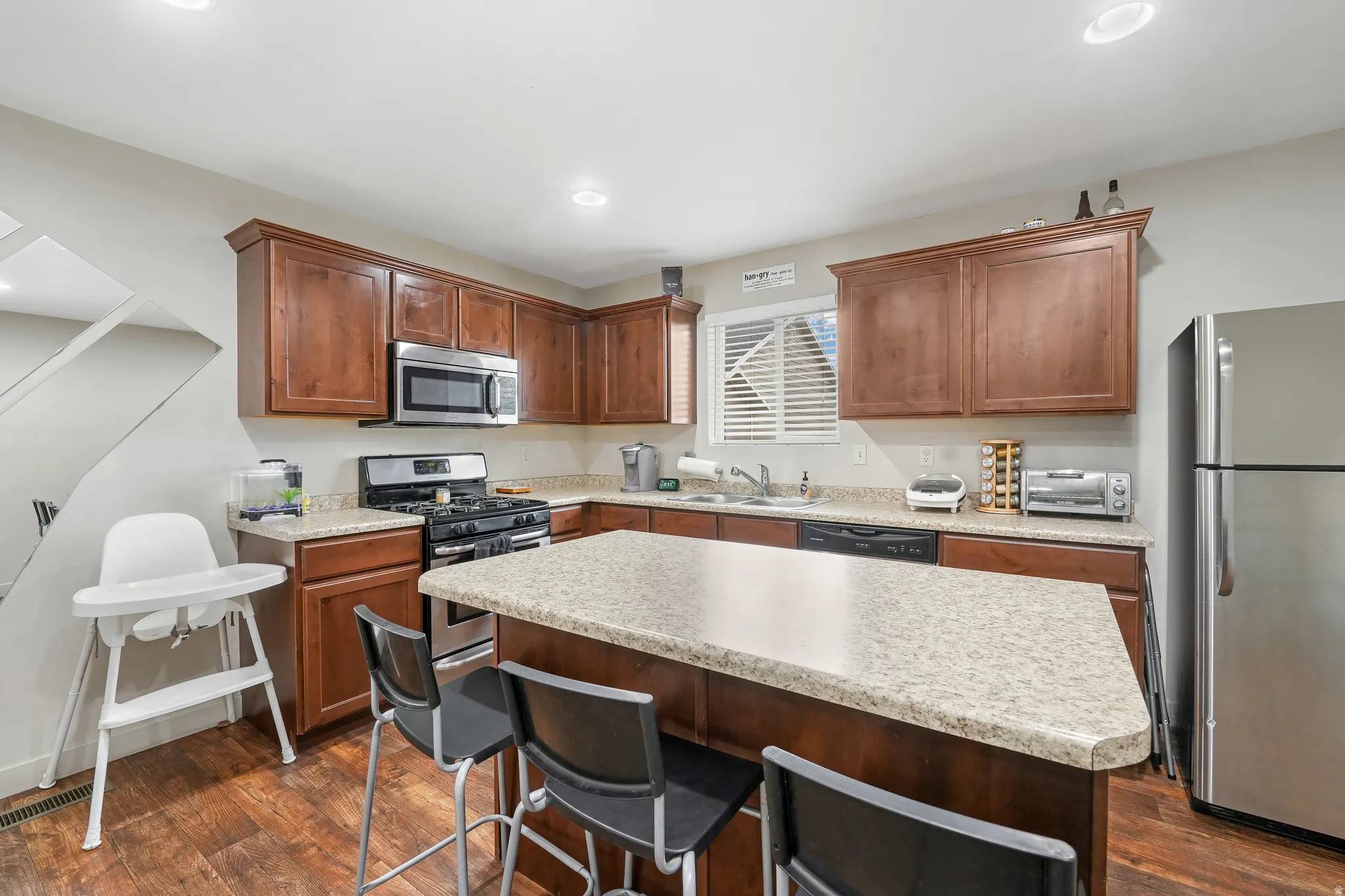 Kitchen featuring wood-finish flooring, recessed lighting, and a window with horizontal blinds
