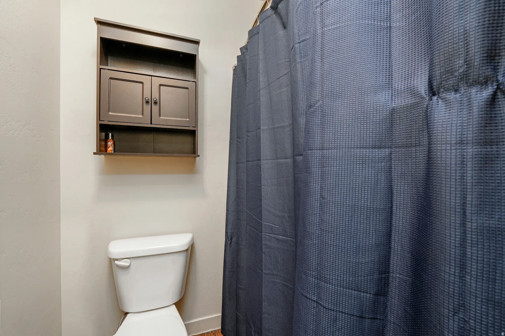 White toilet with a built-in wall cabinet featuring two closed doors and open shelving