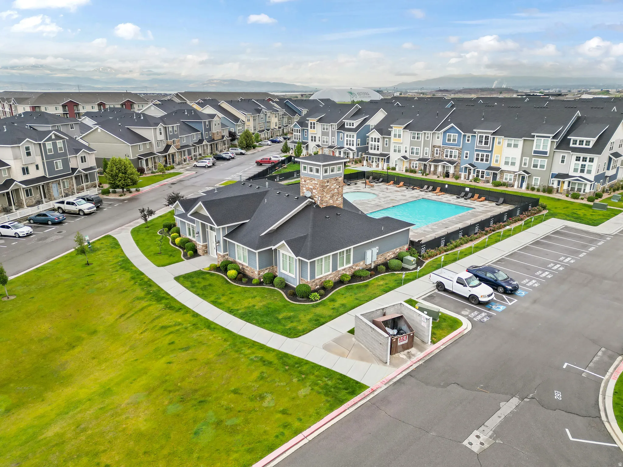 Community clubhouse featuring a stone-clad tower, a swimming pool with an integrated spa, and a paved parking area