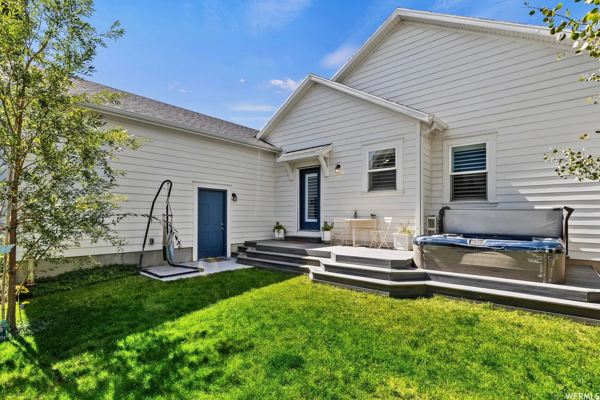 Expansive backyard featuring a tiered deck, built-in hot tub, and a manicured lawn