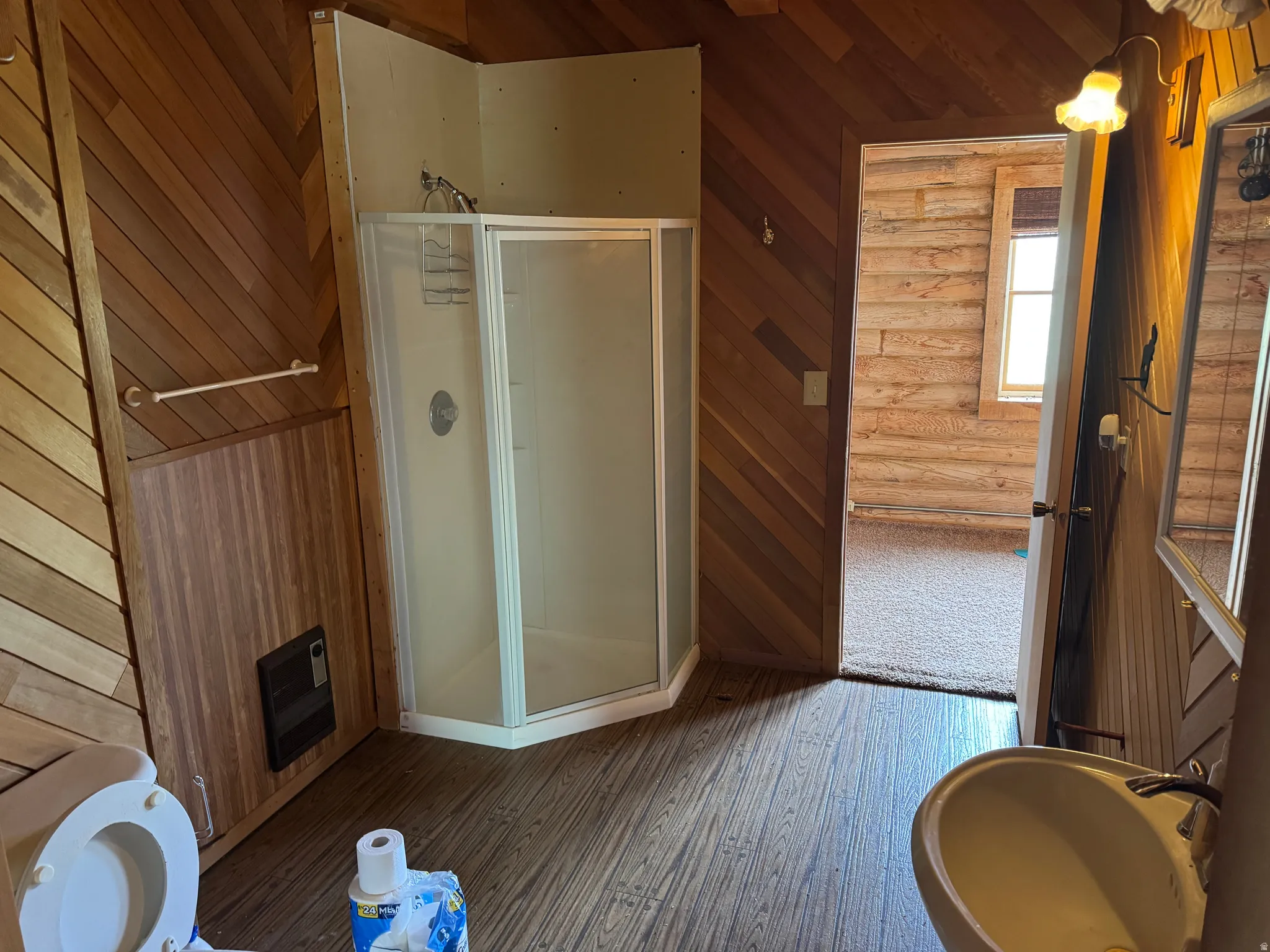Bathroom featuring wood-finish flooring and slatted wood wall paneling