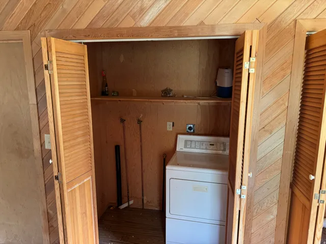 Dedicated utility closet featuring louvered bi-fold doors, wood paneling, and an integrated shelf