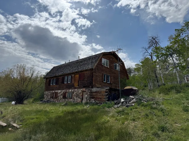 Rustic cabin-style dwelling featuring a gambrel roof and natural wood siding