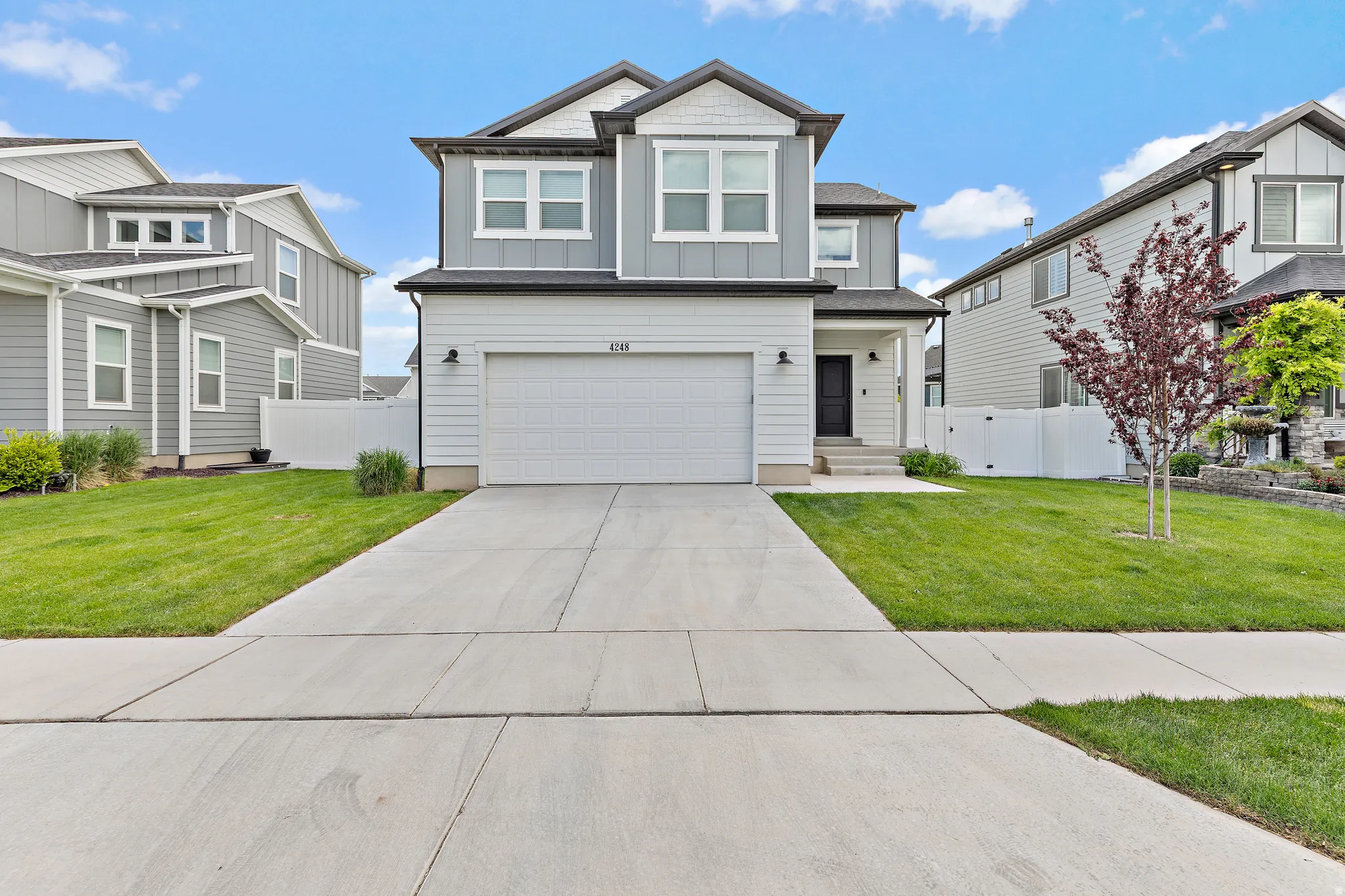 Two-story home with a light gray and white façade, featuring a two-car garage