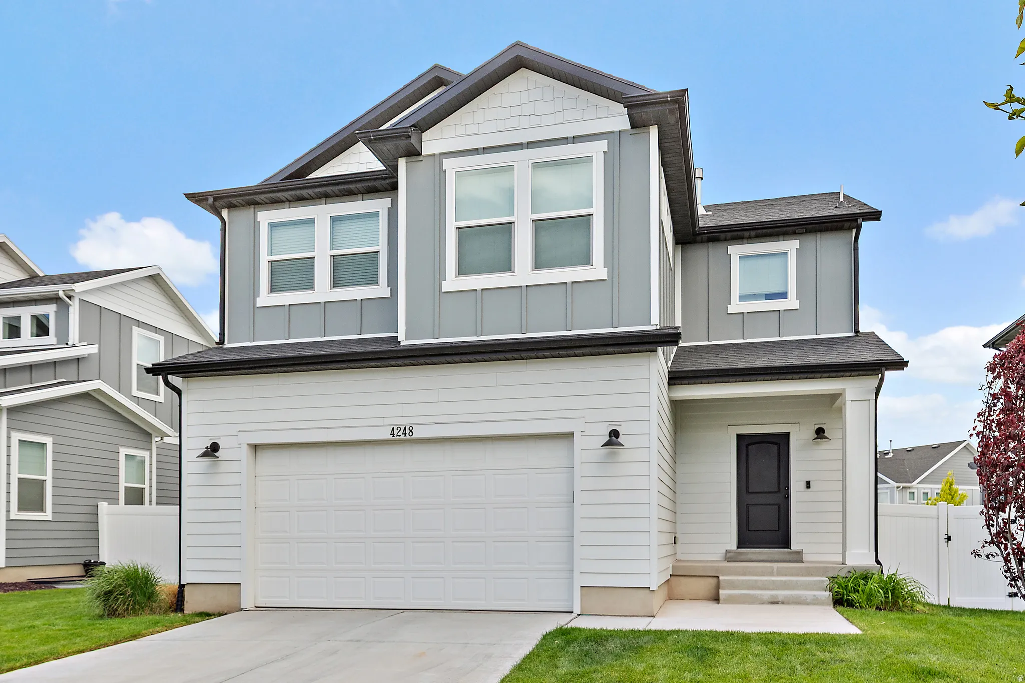 Modern two-story residence featuring a gray and white exterior with vertical and horizontal siding