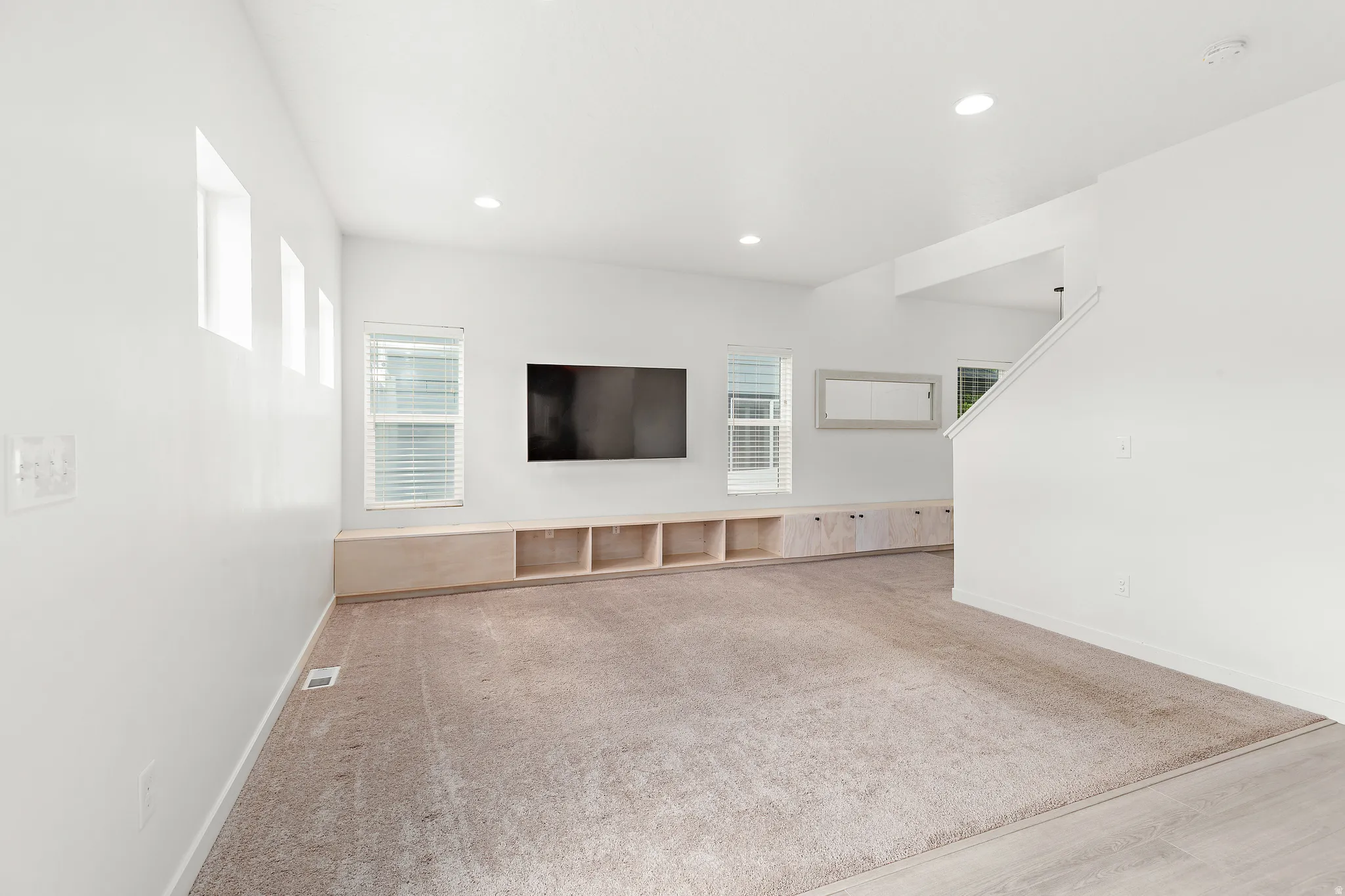 Open-concept living space featuring light-toned carpet and white walls