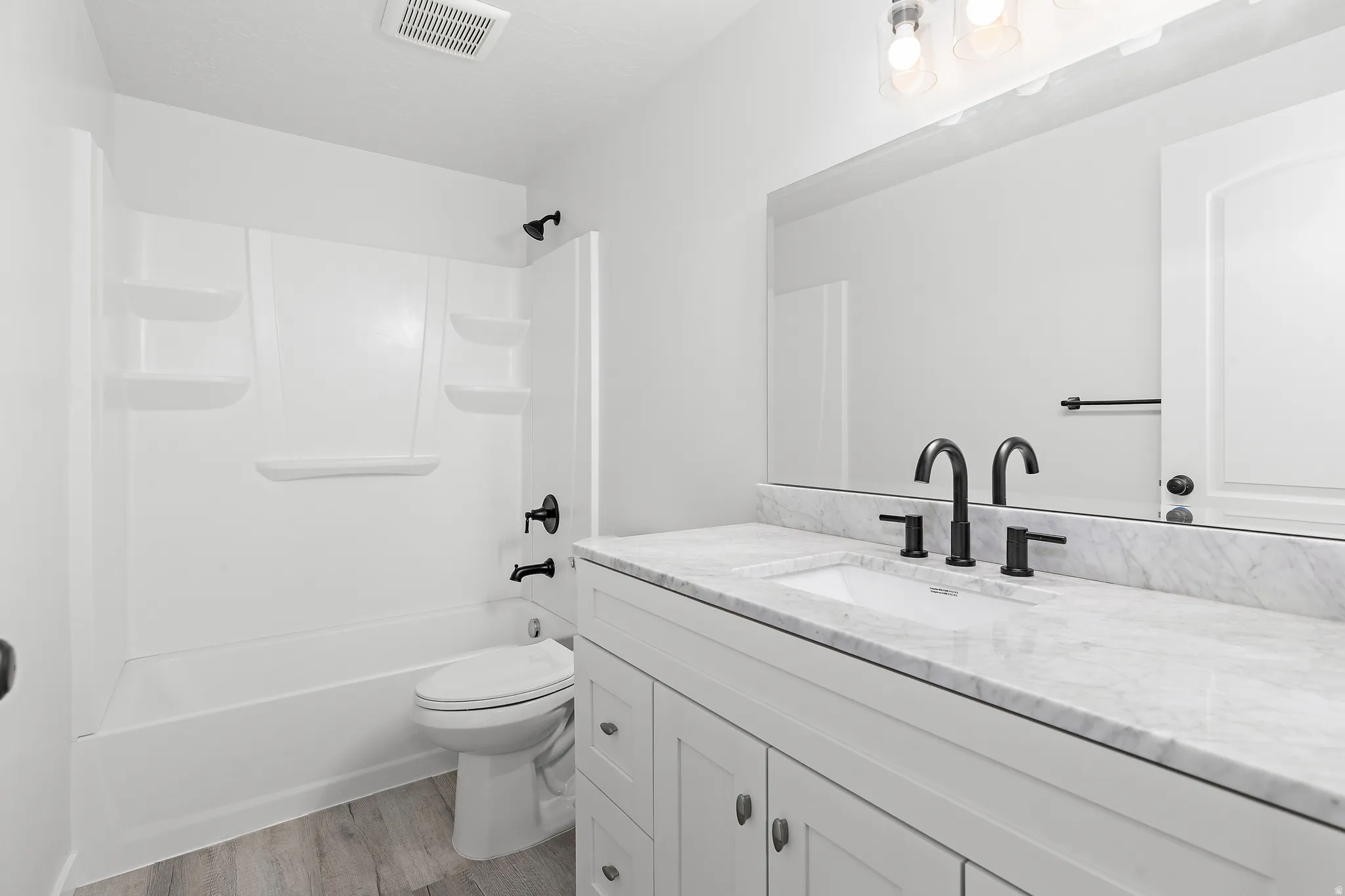 Bathroom featuring a white vanity with a light-toned countertop, a rectangular undermount sink, and matte black fixtures