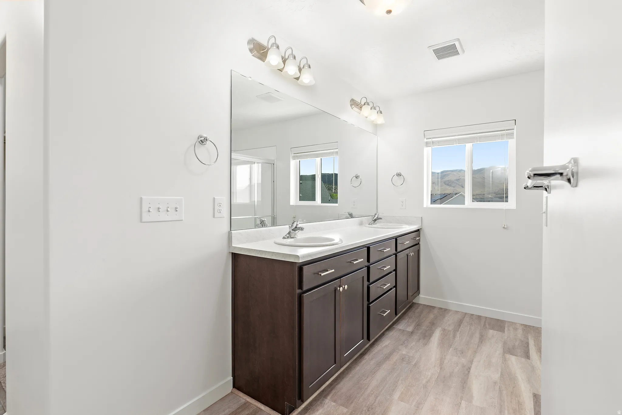 Bathroom featuring a double vanity with dark wood cabinetry, white countertops, and dual undermount sinks