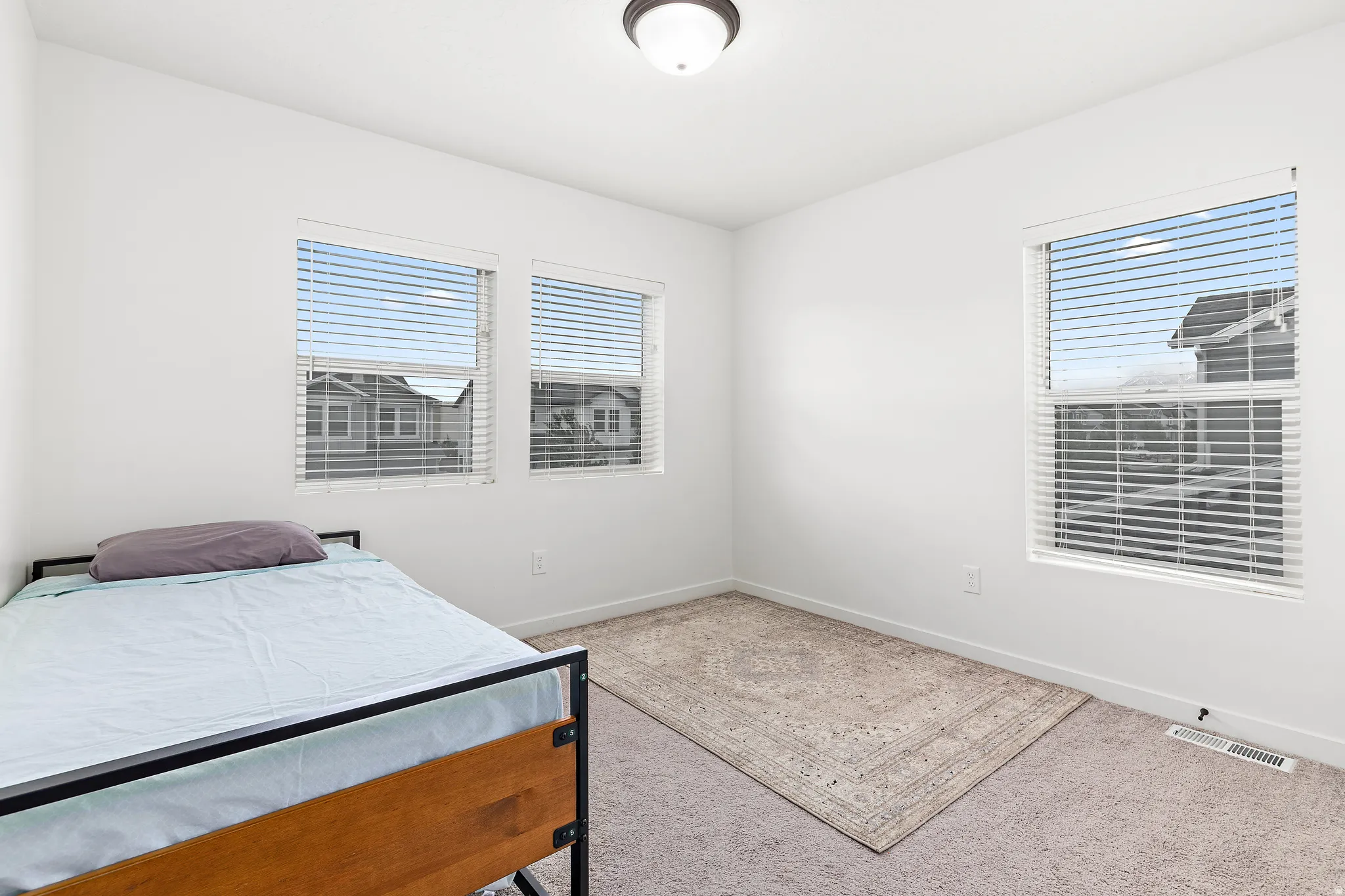 Bright interior space featuring white walls, textured carpeting, and a flush-mount ceiling light fixture