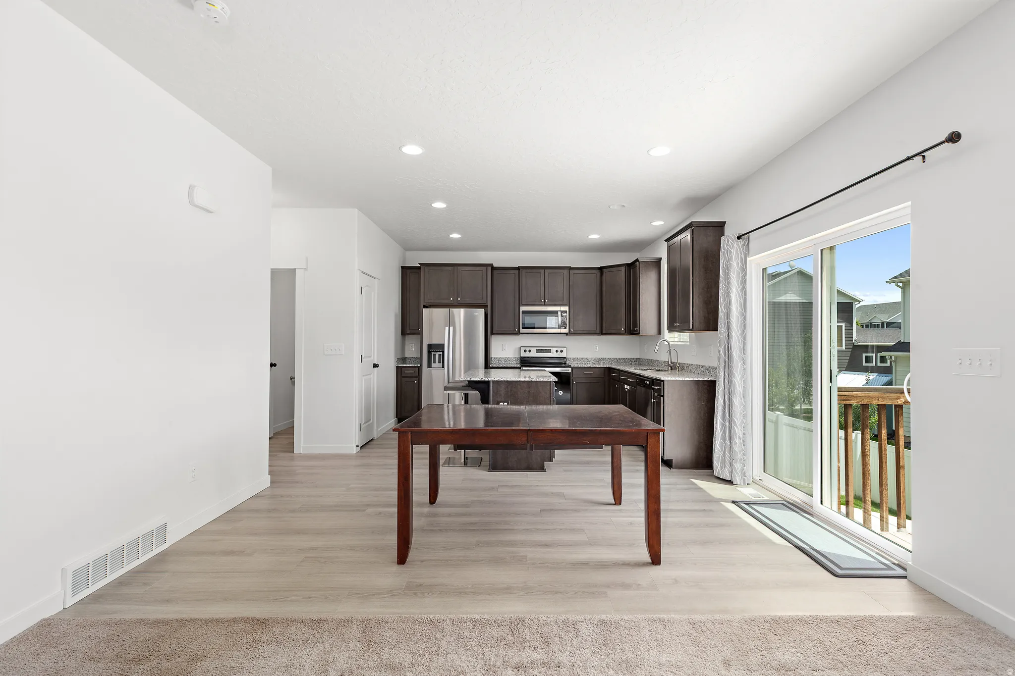Open-concept kitchen and dining area with dark wood cabinetry, granite countertops, and stainless steel appliances