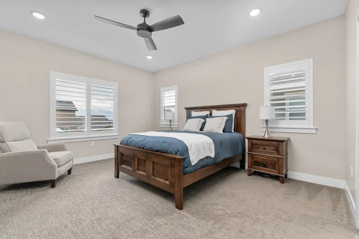 Carpeted room featuring a ceiling fan, recessed lighting, and two windows with white plantation shutters