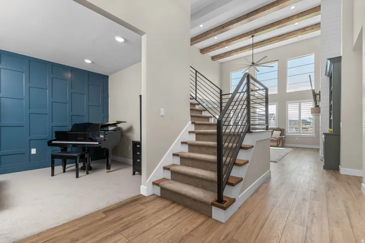 Grand entryway featuring wood-finish flooring, a contemporary staircase with metal balusters, and a beamed vaulted ceiling with recessed lighting