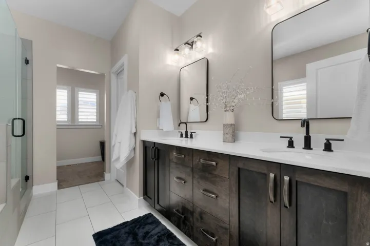 Dual vanity with dark wood-finish cabinetry, white countertops, and matte black fixtures
