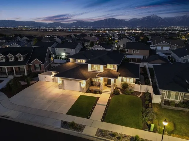 Contemporary single-family residence featuring a stone and stucco exterior, an attached two-car garage, a concrete driveway, a sidewalk, and a manicured lawn with landscaping