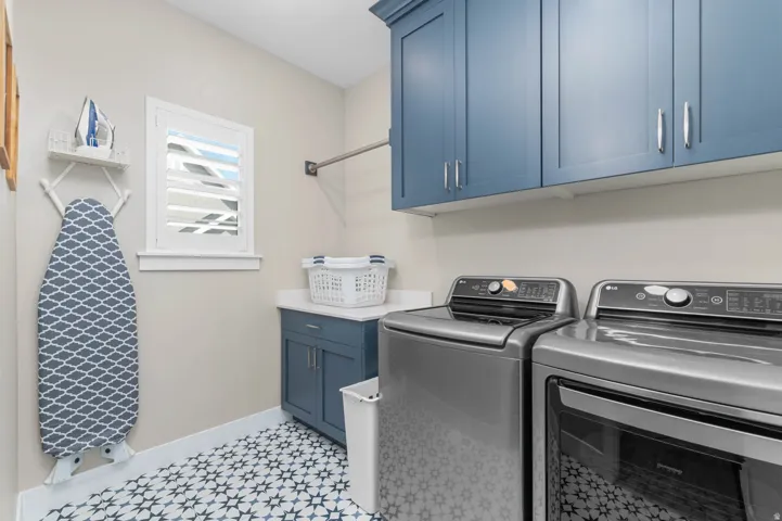 Laundry room featuring pattern tile flooring, a built-in lower cabinet with a solid surface countertop, and upper cabinetry