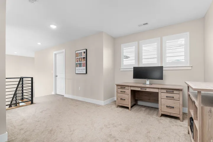Spacious bonus room featuring neutral carpeting, recessed lighting, and a modern horizontal metal stair railing