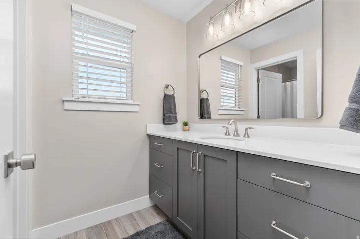 Bathroom featuring a single vanity with gray cabinetry, white countertop, and brushed nickel hardware