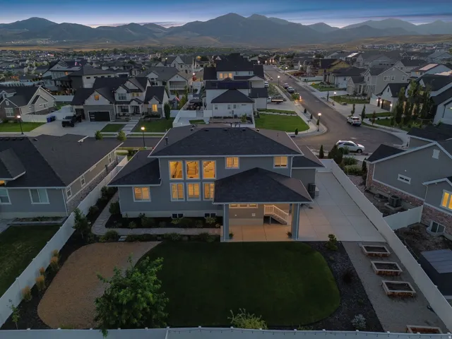 Contemporary two-story residence featuring a covered patio, extensive window arrays, and a manicured lawn