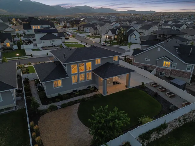 Contemporary home featuring a spacious backyard with a manicured lawn, gravel patio, and raised garden beds