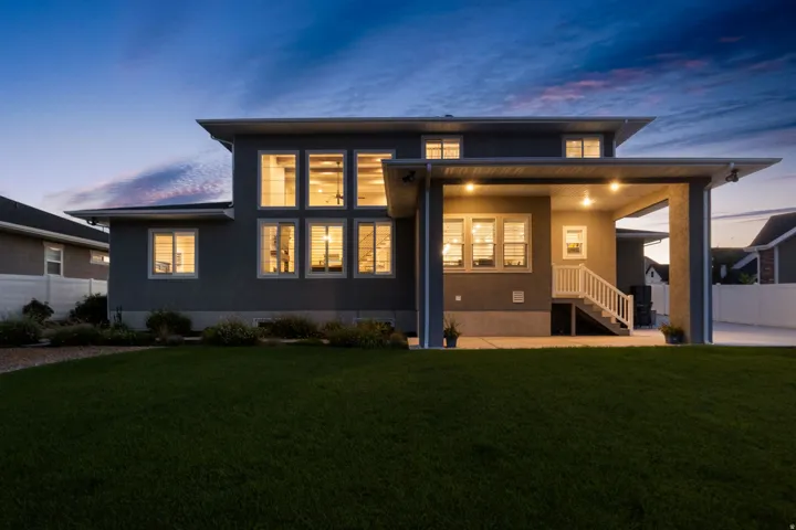 Modern exterior featuring multi-paned windows, a covered patio with recessed lighting, and a well-maintained lawn