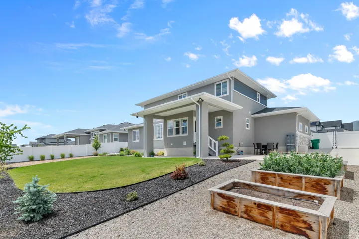 Expansive backyard featuring a manicured lawn, gravel pathways, and raised wooden garden beds
