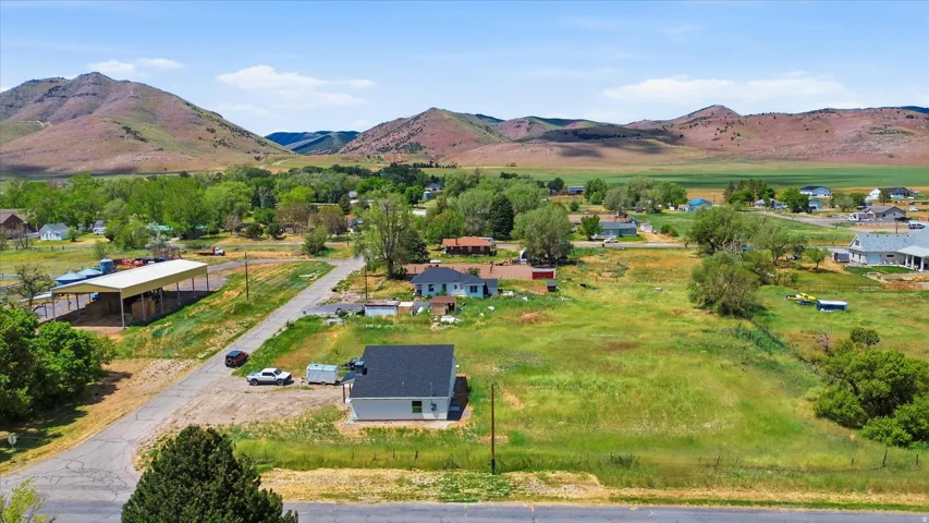 Expansive lot with mountain backdrop, surrounded by green fields and distant homes