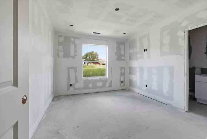 Room under construction featuring an unpainted door, a single window, and visible drywall with mudding