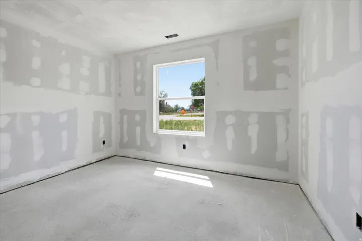 Unfinished interior space featuring drywall with taped and mudded seams, an unpainted concrete subfloor, and a single-pane window