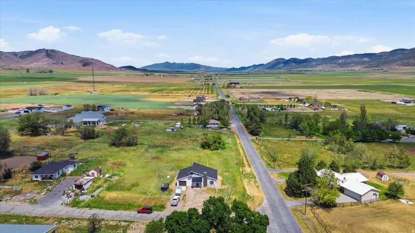 Rural landscape featuring a paved road, scattered residences, and distant mountains