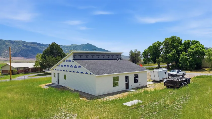 Newly constructed residence featuring white siding, a dark shingle roof, and multiple windows