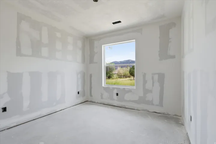 Unfinished interior room featuring drywall installation, a modern window, and an outdoor landscape