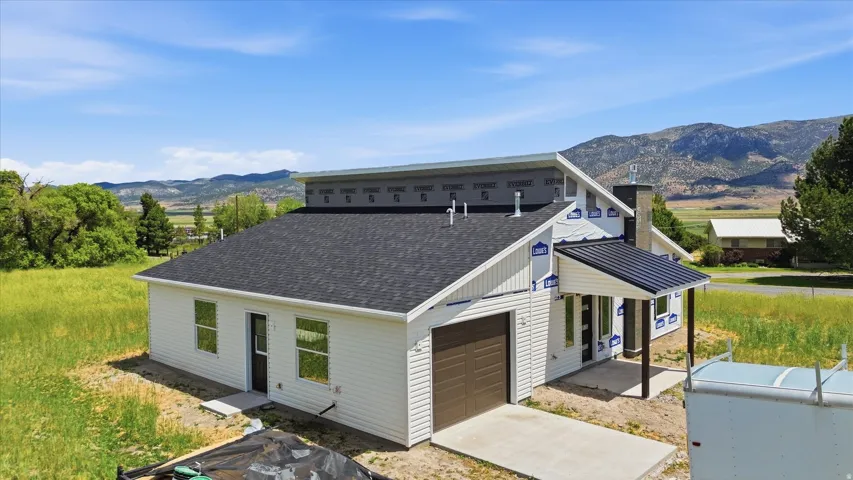 New construction with white siding, dark shingle roofing, and an attached garage