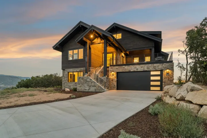 Contemporary multi-level residence featuring a dark wood exterior, stone facade, and a concrete driveway