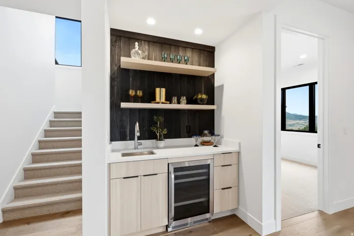 Integrated wet bar featuring a beverage refrigerator, sink, and wood-finish cabinetry