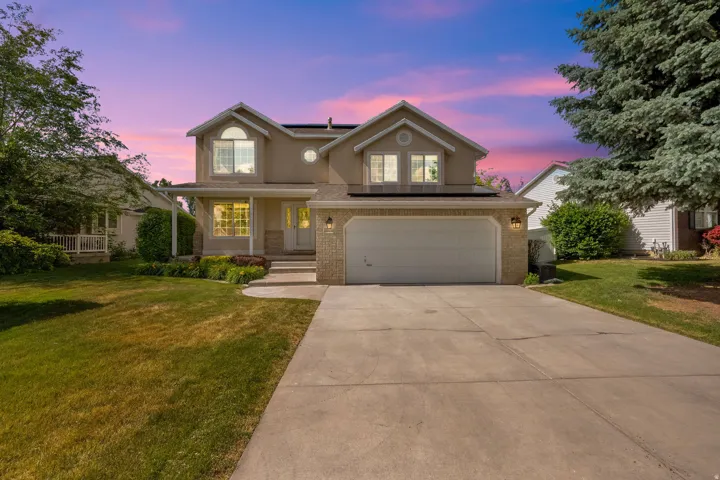 Two-story residence featuring a stucco and brick exterior, an attached two-car garage, and a concrete driveway