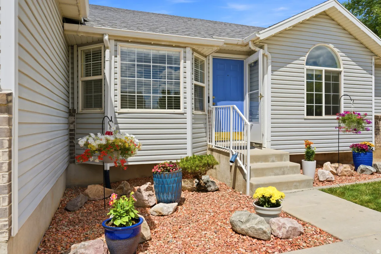 Property exterior featuring light gray siding, a prominent bay window, and a bright blue entry door