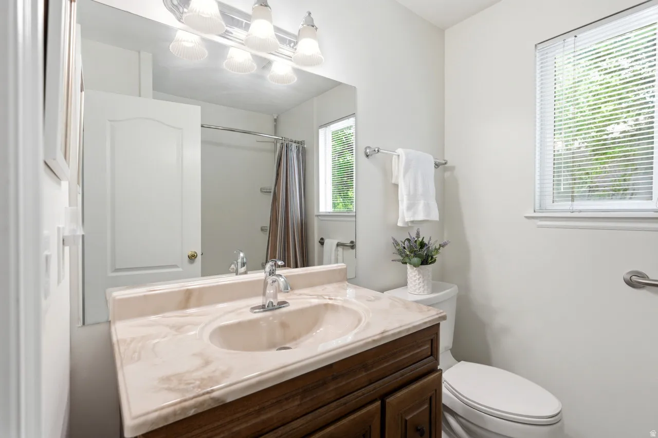 Bathroom featuring a single vanity with a patterned countertop, integrated sink, and wood-finish cabinetry