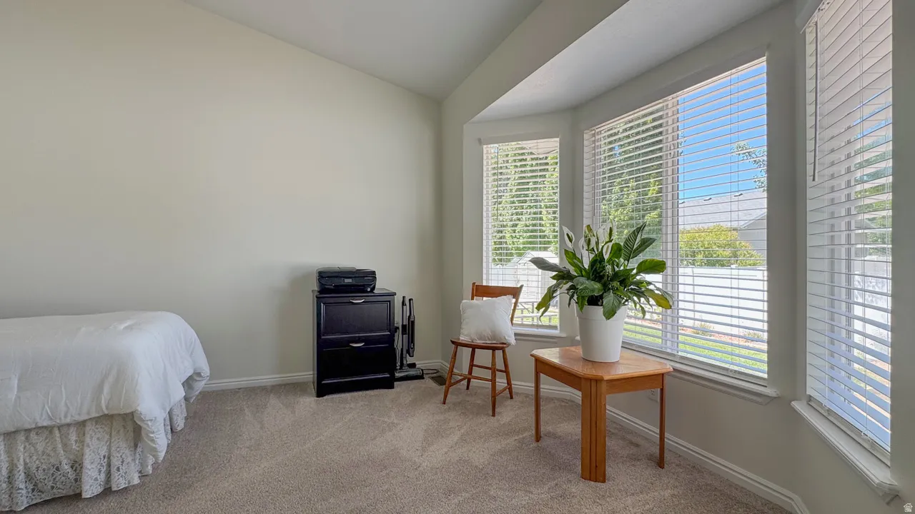 Room featuring a bay window with multiple panes, light-colored walls, sloped ceiling, light-toned carpeting, and white trim