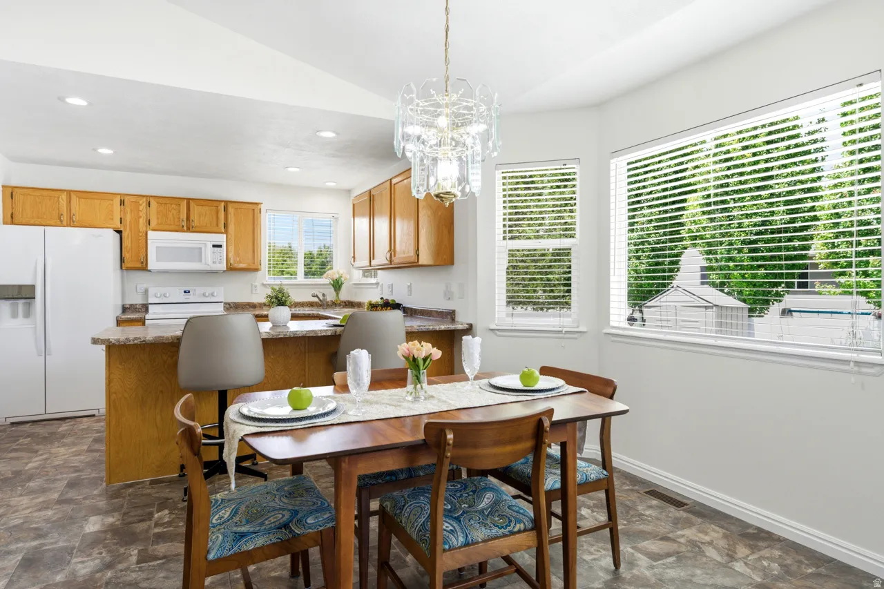 Dining area featuring a contemporary chandelier, wood-finish flooring, and ample natural light from multiple windows