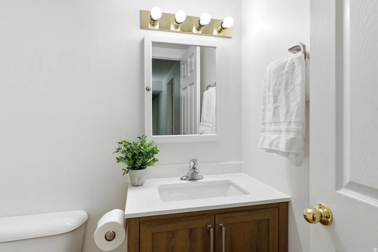Bathroom vanity featuring a white countertop with an integrated sink, wood-finish cabinetry, and a chrome faucet