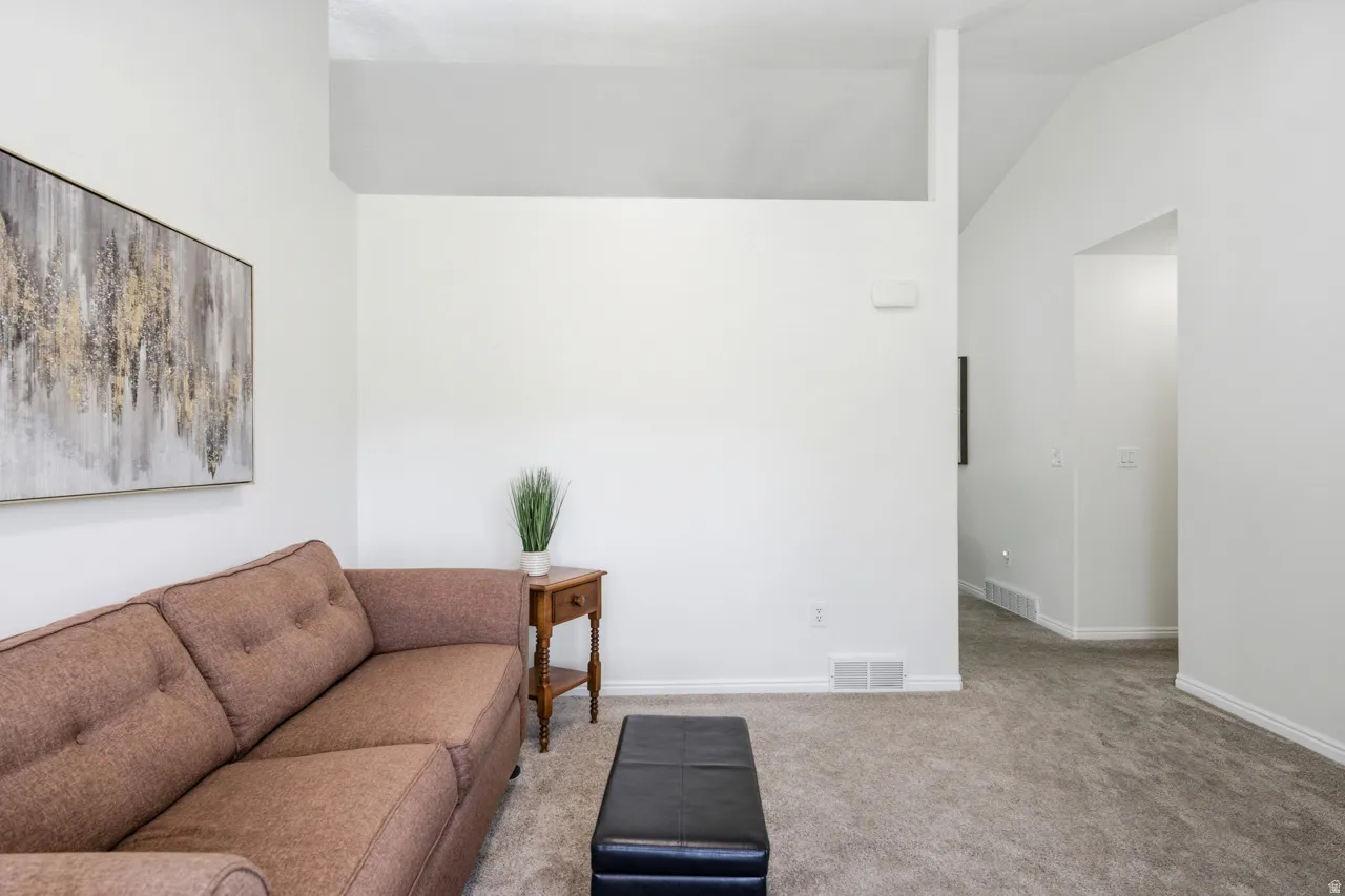 Spacious living area featuring neutral carpeting and crisp white walls