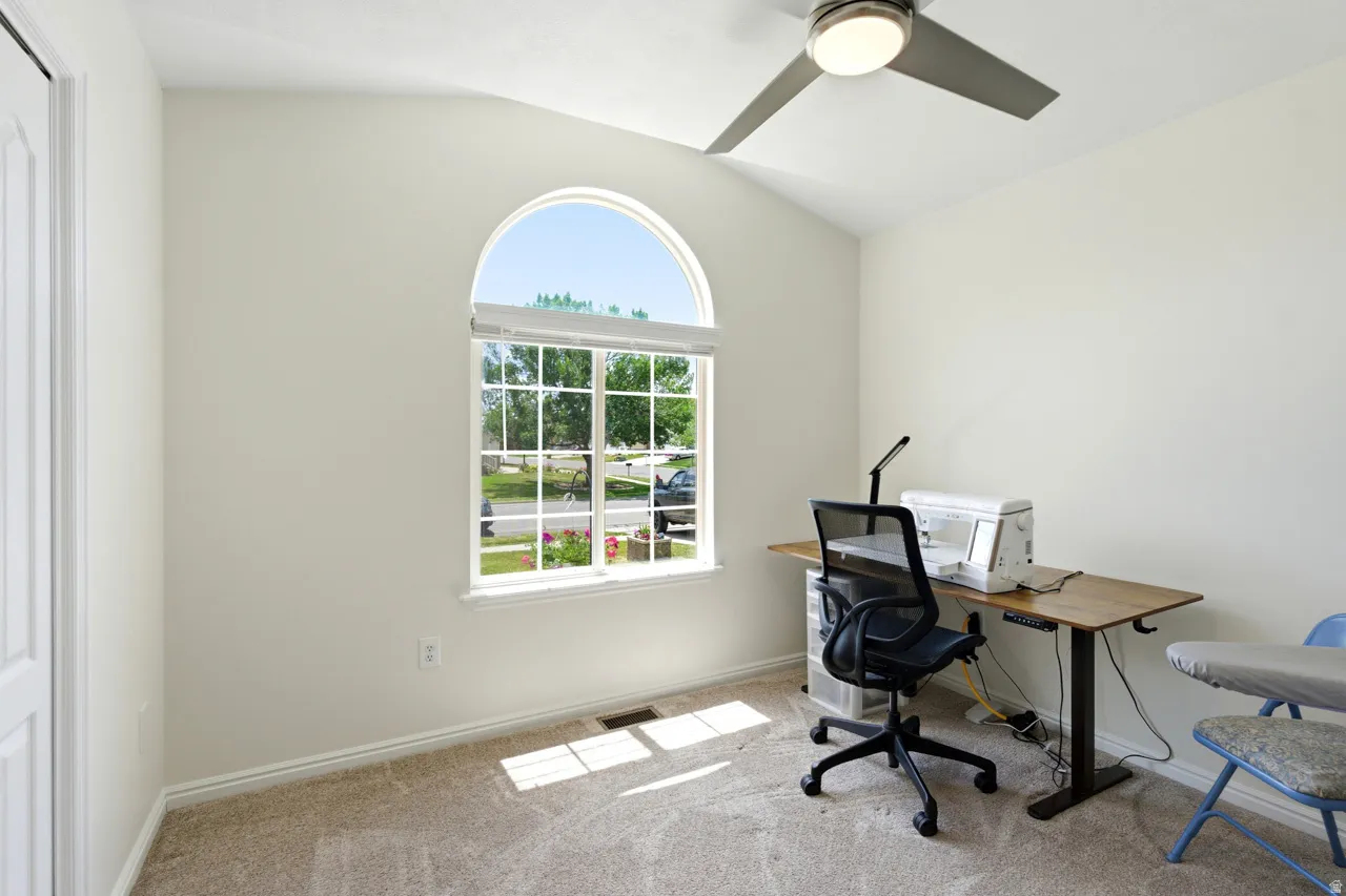 Arch-top window with grid pattern, vaulted ceiling, and ceiling fan