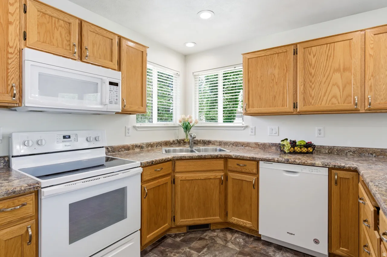 Kitchen featuring wood-finish cabinetry, patterned countertops, and a double basin stainless steel sink
