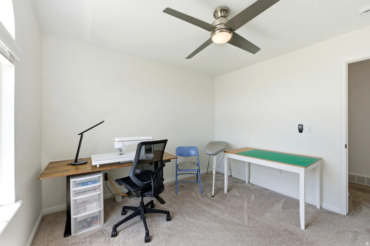 Spacious room featuring neutral carpeting, white walls, and a ceiling fan with integrated lighting
