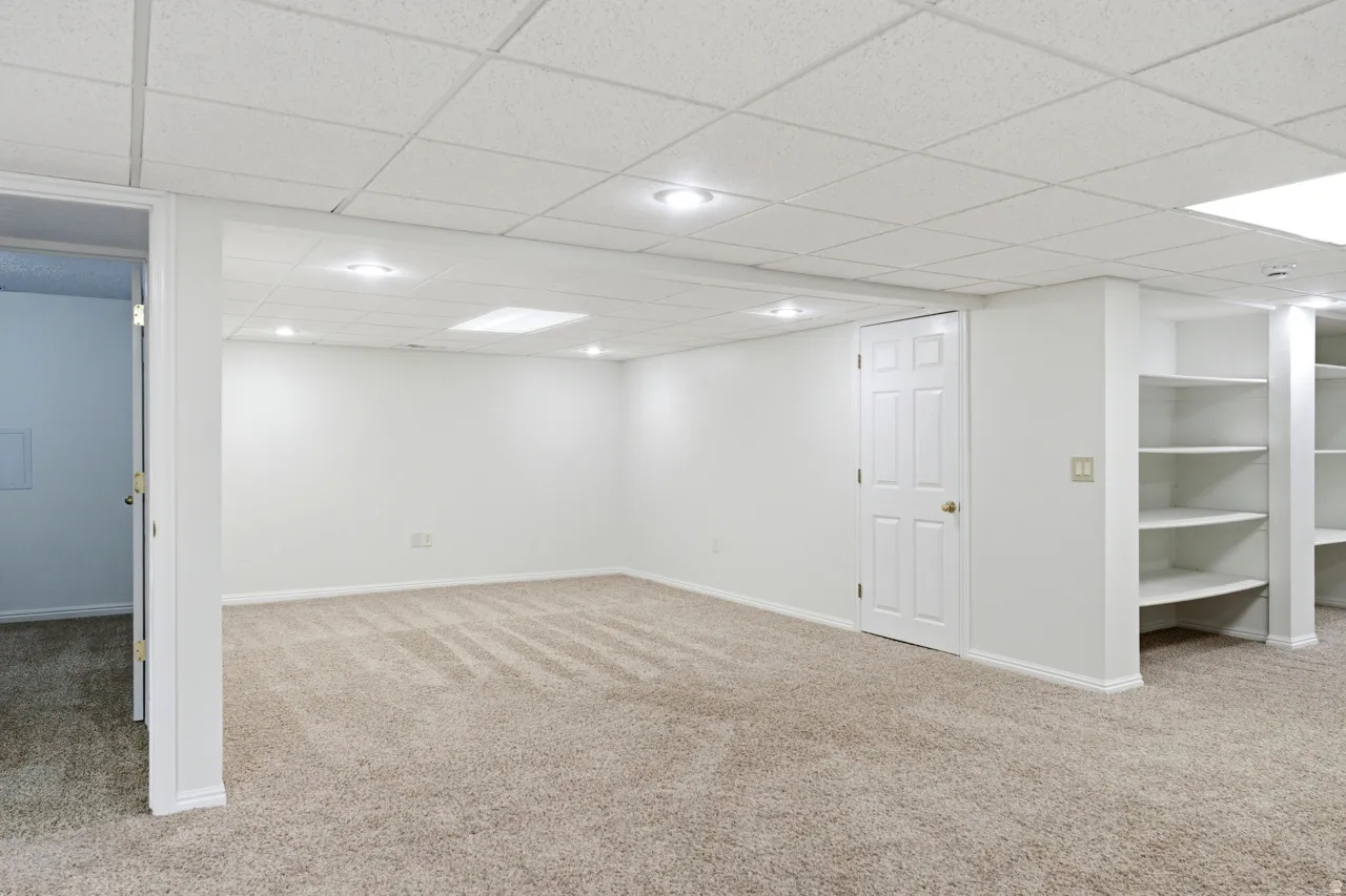 Spacious room featuring carpeting, white walls, recessed lighting, and built-in shelving