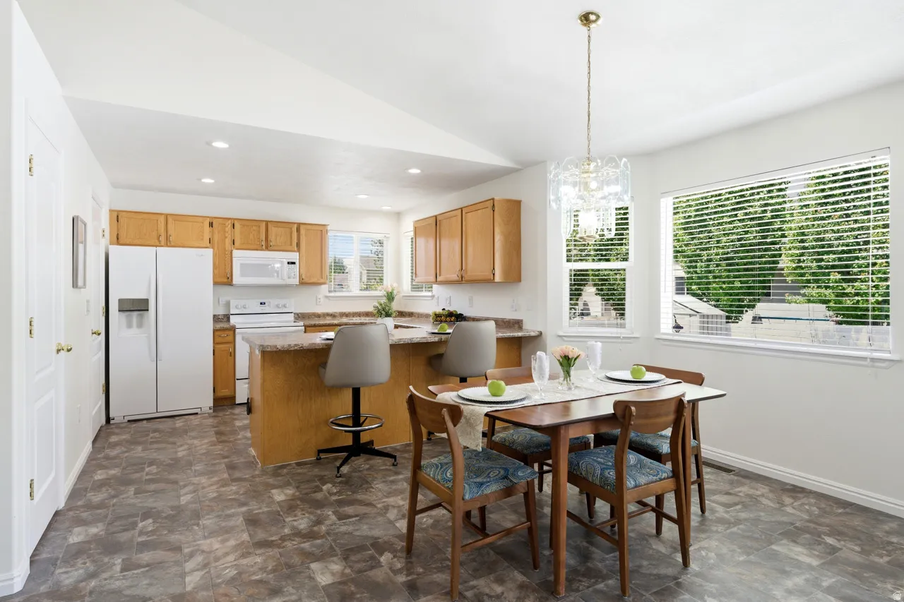 Kitchen and dining area featuring vaulted ceilings, recessed lighting, and wood-finish flooring