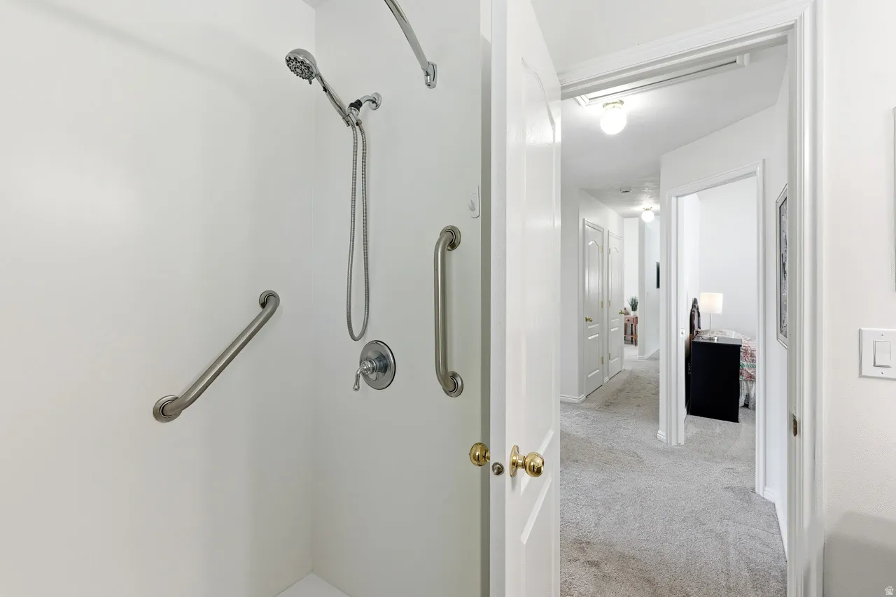 Walk-in shower with integrated grab bars, handheld showerhead, and wall-mounted controls