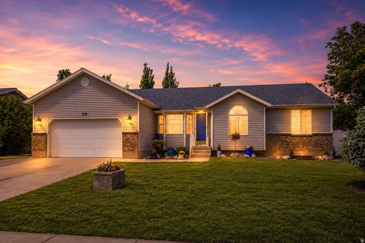 AI Enhanced Twilight.  Ranch-style residence featuring a prominent two-car garage with overhead lighting